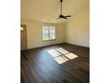 Bright living room featuring hardwood floors, a modern ceiling fan, and large windows at 415 Dove Ln, Social Circle, GA 30025