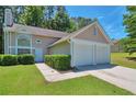 Two-story home features a two-car garage, front yard with bushes, and a sidewalk leading to the front door at 4879 Ardsley Dr, Lithonia, GA 30038