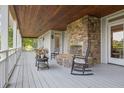 Inviting outdoor porch with a stone fireplace, rocking chair, wood ceiling and serene ambiance at 2216 Trammel Rd, Cumming, GA 30041