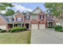Lovely exterior view of a brick townhome featuring a two-car garage and green landscaping at 1102 Lexington Dr, Roswell, GA 30075