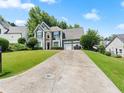 Two-story home with manicured lawn and three-car garage and a long driveway in a suburban neighborhood at 530 Camber Woods Dr, Roswell, GA 30076
