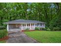 Charming single-story home with a covered carport, landscaped front yard, and red front door at 2383 Edgewater Sw Dr, Atlanta, GA 30311