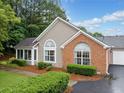 View of home featuring brick facade, neutral siding, an attached garage, and mature landscaping at 4512 Orchard Trce, Roswell, GA 30076
