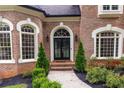 Close-up of brick home's entrance featuring an arched doorway and manicured landscaping at 9360 Nesbit Lakes Dr, Alpharetta, GA 30022
