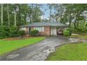 Charming brick home features a well-manicured lawn and mature trees, complemented by a convenient attached carport at 1849 Clay Sw Rd, Mableton, GA 30126