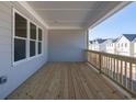 Spacious outdoor patio with wooden flooring, grey wood-paneled wall, and a view of neighboring homes at 1980 Deco Dr, Kennesaw, GA 30144