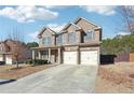 Two-story brick home with a two-car garage and a driveway, set against a partly cloudy sky at 7434 Absinth Dr, Atlanta, GA 30349