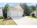 Side view of a house with a two-car garage, and driveway, surrounded by green lawn and shrubs at 428 Redwood Trl, Canton, GA 30114