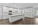 Modern kitchen featuring white cabinets, quartz countertops, stainless steel appliances, and a large island at 6104 Marigold Way, Atlanta, GA 30349