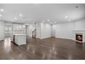 Open-concept living room with hardwood floors, a modern kitchen, and a cozy fireplace at 6104 Marigold Way, Atlanta, GA 30349