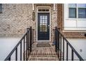 Inviting front entry featuring a black front door, brick steps, and wrought iron railings at 6404 Brookside Se Blvd, Mableton, GA 30126