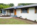 Inviting exterior view of a white brick home featuring decorative wooden shutters and a vibrant orange front door at 2786 Knollview Dr, Decatur, GA 30034