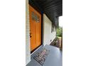 Close-up of a striking orange front door with glass panes, accented by a 'Welcome' mat on the gray porch at 2786 Knollview Dr, Decatur, GA 30034
