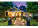 Evening view of a charming home featuring manicured landscaping and an inviting front porch with string lights at 486 Haas Se Ave, Atlanta, GA 30316