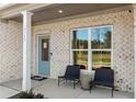 Inviting front porch with chairs, a blue door, a welcome mat, and white brick exterior walls at 5430 Hyde Rd, Cumming, GA 30040