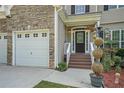 Inviting front entrance with a decorative door, landscaped garden, and a two-car garage on a sunny day at 7052 Camp Falls Ct, Winston, GA 30187