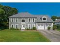 Two-story home featuring a manicured lawn, a two-car garage, and a classic gray facade with white trim at 5223 Willow Ridge Dr, Woodstock, GA 30188