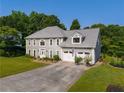 Two-story home featuring a large manicured lawn, a two-car garage, and a classic gray facade at 5223 Willow Ridge Dr, Woodstock, GA 30188