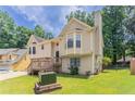 Back of the house with a well-manicured lawn, trees, and a neutral color scheme at 1214 Tyne Way, Stone Mountain, GA 30088