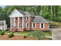 Brick home with white columns, attached garage, and professionally landscaped front yard on wooded lot at 5276 Beechwood Ct, Marietta, GA 30068