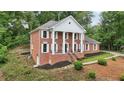 A traditionally styled brick home showcasing white columns and shutters, with a meticulously maintained lawn at 5276 Beechwood Ct, Marietta, GA 30068