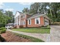 Traditional brick home with attached garage and columned portico, set amidst lush greenery and mature trees at 5276 Beechwood Ct, Marietta, GA 30068