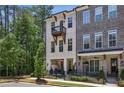 Stylish townhome features a private balcony and covered patio, complemented by lush greenery and a black metal fence at 408 Townly Ct, Alpharetta, GA 30009