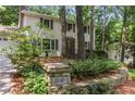 View of a two-story home with trees surrounding it and a stone wall in the front at 5240 Arrie Way, Atlanta, GA 30360
