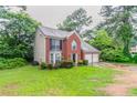 View of the side of a brick home, featuring a two-car garage and well-maintained front lawn at 2191 Phillips Rd, Lithonia, GA 30058