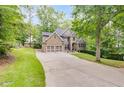 Beautiful home with mature trees, manicured lawn, long driveway, and a mix of stone and siding on the exterior at 1058 Magnolia Dr, Villa Rica, GA 30180