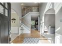 Bright foyer with hardwood floors, white trim, arched doorways, and an elegant staircase to the second floor at 1641 Rocky Knoll Ln, Dacula, GA 30019