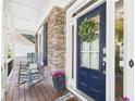 Charming front door with a wreath, rocking chairs, and stone detailing around the porch at 122 White Spruce Ct, Dallas, GA 30157