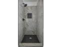 Modern bathroom shower featuring tiled walls, matte black fixtures, and a black hexagon tiled floor at 515 Allens Landing Ct, Lawrenceville, GA 30045