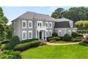 Elegant home featuring a manicured lawn, decorative shrubbery, and a classic façade with a small balcony at 4720 Cliffside Ct, Marietta, GA 30067