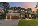Charming two-story home at dusk with a manicured lawn, a two-car garage, and beautiful landscaping at 1268 Harris Road Rd, Lawrenceville, GA 30043