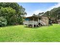 A grassy backyard with a wooden deck and stairs, and a car port in the distance at 1550 Bells Ferry Rd, Marietta, GA 30066
