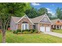 Charming home with stone accents, two car garage, bay window, and well-maintained landscaping in a lush, green setting at 607 Little Shoals Ct, Canton, GA 30115