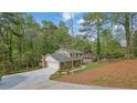 The home has a long driveway, brick facade, and a two-car garage amid a backdrop of lush greenery at 3512 Hidden Acres Dr, Atlanta, GA 30340
