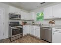 Functional kitchen featuring white cabinets, stainless steel appliances, and durable flooring at 350 Birch Rill Dr, Alpharetta, GA 30022