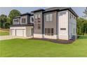 Modern two-story home with three-car garage, well-maintained lawn and mature trees at 52 Deer Canyon Dr, Auburn, GA 30011