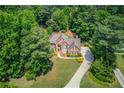 Aerial view of a brick home surrounded by lush greenery on a large lot with a long driveway at 1721 Crowes Lake Ct, Lawrenceville, GA 30043