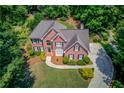 Aerial view of brick home with well maintained landscaping, gray shingle roof, and long paved driveway at 1721 Crowes Lake Ct, Lawrenceville, GA 30043