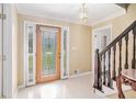 Inviting foyer with tile flooring, glass-paneled door, staircase, and elegant light fixture at 4837 Mystere Sw Cir, Lilburn, GA 30047