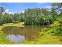 Scenic view of a tranquil pond reflecting the surrounding trees and sky, creating a serene and picturesque landscape at 6160 Campbellton Redwine Rd, Chattahoochee Hills, GA 30268
