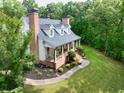 Elegant home with a charming front porch, lush landscaping, and a serene setting surrounded by trees and greenery at 5588 Rhododendron Trl, Douglasville, GA 30135