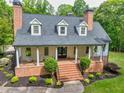 Stunning home with a welcoming brick porch, elegant white columns, and beautiful landscaping surrounded by lush greenery at 5588 Rhododendron Trl, Douglasville, GA 30135