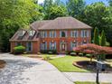 Attractive red brick home featuring shutters, lush landscaping and a curving driveway at 2910 Leeds Garden Ln, Alpharetta, GA 30022