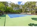 A blue and green outdoor tennis court surrounded by trees at 2910 Leeds Garden Ln, Alpharetta, GA 30022