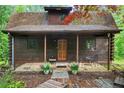 Inviting log cabin featuring a cozy front porch with stone accents and a welcoming pathway at 15 Bailey St, Whitesburg, GA 30185