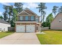 A two-story brick home featuring a two-car garage, surrounded by a well-manicured lawn and wooden fence at 154 Stephens Mill Dr, Dallas, GA 30157